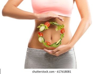 Fit, young woman holding a circle made out of vegetables over her abdomen 