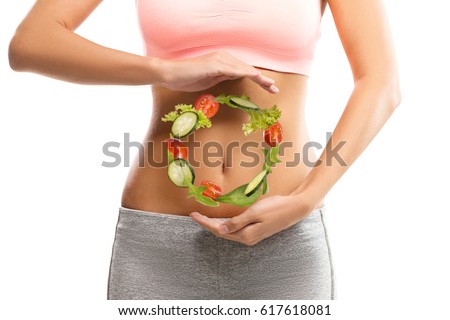 Fit, young woman holding a circle made out of vegetables over her abdomen 