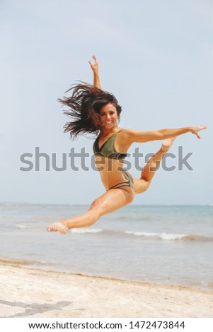 Fit young woman jumping gracefully on the beach on a sunny day