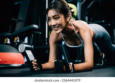 Fit young woman maintaining a plank position on a stability ball to improve core strength and balance during her indoor gym workout, exercise in dark gym background - Shutterstock ID 2364441079