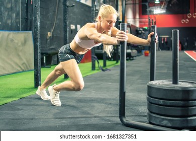 Fit Young Woman Pushing The Weight Sled At Gym