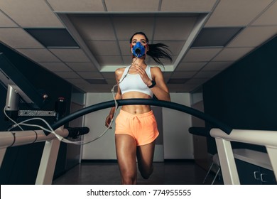 Fit Young Woman Running On Treadmill With A Mask. Athlete Examining Her Performance In Sports Science Lab.