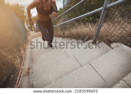 Fit young woman running up the stairs outdoors in the morning. Sporty young woman having a vigorous physical training.