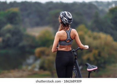 Fit young woman wearing sportswear standing with her bicycle on rocky background at autumn day - Shutterstock ID 1862689309