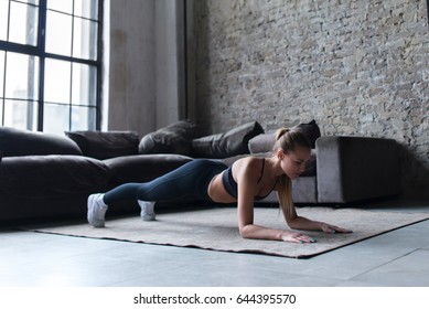 Fit Young Woman Wearing Sportswear Working Out At Home Doing Planking Exercise On Carpet