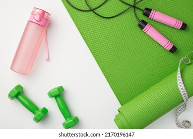 Fitness accessories concept. Top view photo of pink bottle of water green sports mat dumbbells skipping rope and tape measure on isolated white background - Powered by Shutterstock
