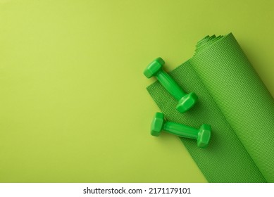Fitness accessories concept. Top view photo of green sports mat and dumbbells on isolated green background with copyspace - Powered by Shutterstock