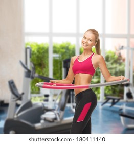 fitness ang gym concept - young sporty woman with hula hoop at gym - Powered by Shutterstock