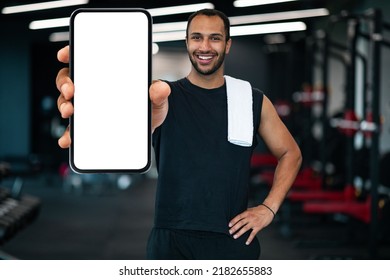 Fitness App. Sporty Black Guy Showing Smartphone With Blank White Screen At Camera, Muscular Handsome African American Athlete Recommending New Mobile Application For Workout Trainings, Mockup