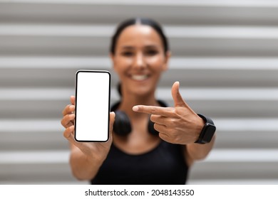 Fitness App. Sporty Fit Young Lady Holding And Pointing At Smartphone With Blank White Screen While Training Outdoors, Smiling Woman Demonstrating Copy Space For Application Design, Mockup - Powered by Shutterstock