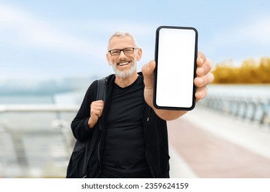 Fitness app. Sporty senior man stand on bridge, show smartphone with blank white screen at camera, handsome elderly athlete recommending new mobile application for workout jogging trainings, mockup - Powered by Shutterstock