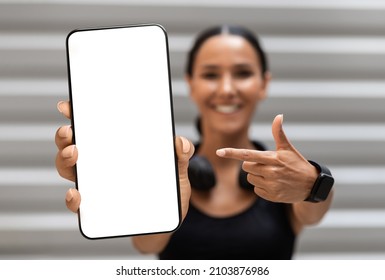 Fitness App. Sporty Young Woman Pointing At Big Blank Smartphone In Hand, Fit Millennial Lady Showing Phone With White Screen, Demonstrating Copy Space, Recommending New Mobile Application, Mockup - Powered by Shutterstock