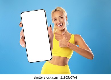 Fitness App. Sporty Young Woman Holding Big Blank Smartphone And Showing Thumb Up At Camera, Happy Fit Female Recommending Workout Application, Standing On Blue Background, Collage, Mockup