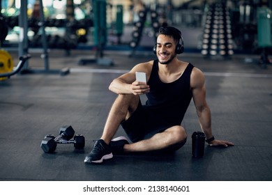 Fitness Application. Smiling Middle Eastern Sportsman Using Smartphone At Gym While Relaxing After Training, Handsome Arab Male Athlete Browsing New Mobile App With Workout Tutorials, Copy Space - Powered by Shutterstock