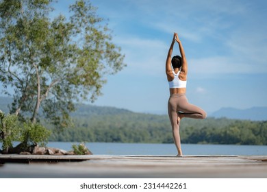 Fitness Asian woman doing yoga in park, Young woman practicing yoga, female happiness in landscape background, Lifestyle of exercise and pose for relax healthy life in the morning nature outdoor - Powered by Shutterstock