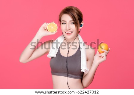 Fitness asian woman with orange fruits concept. She smiling and holding oranges. Beauty face and natural makeup sports bra outfit. Isolated over pink background