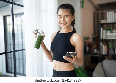 Fitness asian woman using smart phone and drinking organic green smoothie fruit detox for diet after workout exercise
training healthy lifestyle. - Powered by Shutterstock