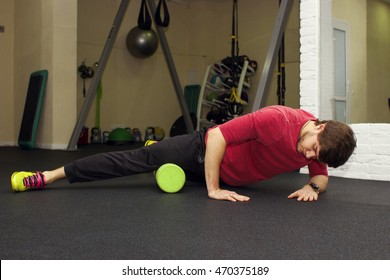 Fitness athletic trainer shows exercises. Handsome man at the gym. Stretching exercises and myofascial relaxation. Sport rehabilitation.