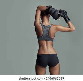 Fitness, back and female boxer in studio for sport, ready and training on gray background. Workout, woman and stretching for exercise with sportswear, boxing gloves and earphones for determination - Powered by Shutterstock