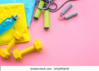 Fitness Background. Equipment For Gym And Home. Jump Rope, Dumbbells, Expander, Mat, Water On Pastel Pink Background Top View Copy Space