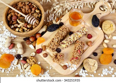 Fitness bars with granola, oatmeal, nuts, dried fruit and honey on the table, top view - Powered by Shutterstock