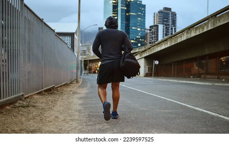 Fitness, black man and walking on city street after running, exercise and gym workout with a hoodie at night. Back of a male athlete in urban Miami for a walk and cardio training with a duffle bag - Powered by Shutterstock