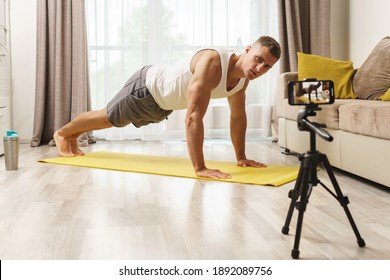 Fitness blogger is streaming or recording video for his subscribers during his home workout - Powered by Shutterstock