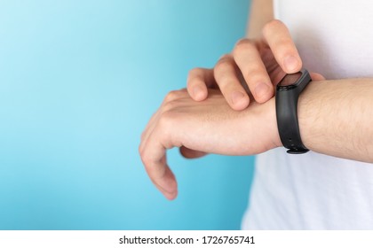 Fitness bracelet on the wrist of a young man. Close-up, horizontal view, blue background for text. Modern technologies for health monitoring. The trend of the younger generation.