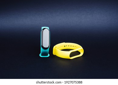 Fitness bracelet for sports on a black background. A smart watch with many different functions. Silicone replacement straps in mint and yellow colors.