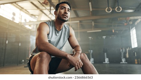 Fitness, breathing and sweating with a tired man in the gym, resting after an intense workout. Exercise, health and fatigue with a young athlete in recovery from training for sports or wellness - Powered by Shutterstock