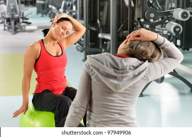 Fitness Center Senior Woman With Trainer Stretching On Swiss Ball