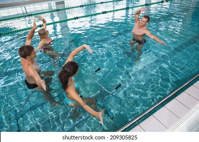 Fitness class doing aqua aerobics on exercise bikes in swimming pool at the leisure centre