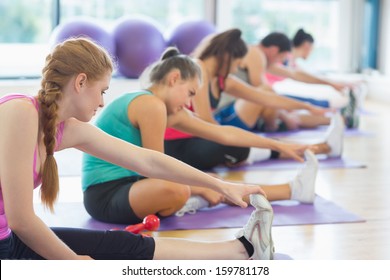 Fitness Class And Instructor Stretching Legs In Bright Exercise Room