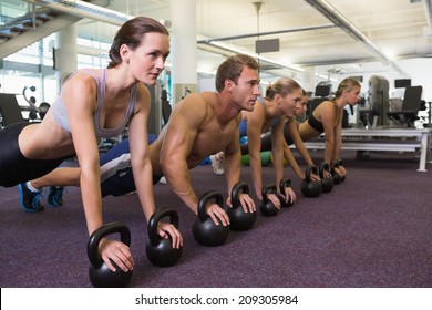 Fitness Class In Plank Position With Kettlebells At The Gym