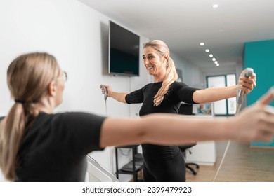 fitness client smiling while holding body composition scale analyzer handles Inbody test, extending arms towards the trainer in a EMS - Studio. - Powered by Shutterstock