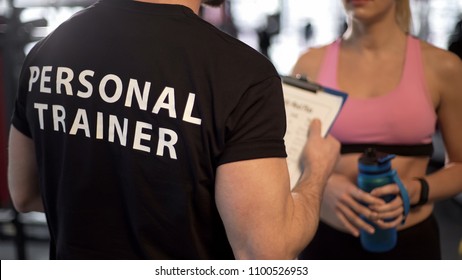 Fitness Coach Explaining Training Program And Schedule To Female Client In Gym