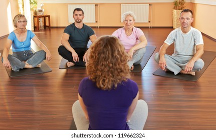 Fitness coach giving group yoga instructions in a gym - Powered by Shutterstock