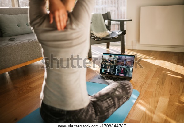 Fitness coach teaching yoga online to group\
of people. Yoga trainer demonstrating yoga poses to students via\
video conference.