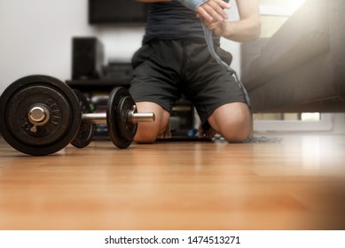 Fitness Concept. Dumbbell On The Floor. Man Starting Strenght And Boxing Training At Home. Athlete Putting Wraps On Hand. Motivation To Act. Determination, Challenge. 