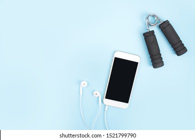 Fitness Concepts. Exercise to lose weight with a smartphone, earphone on a blue background. With copy space. - Shutterstock ID 1521799790