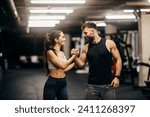 A fitness couple is celebrating success and giving bro handshake in a gym.