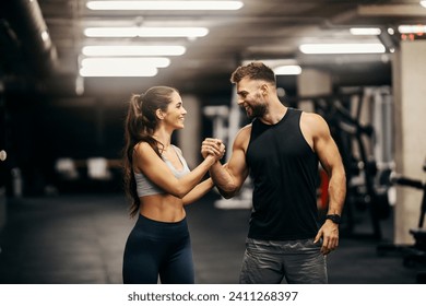 Una pareja de fitness está celebrando el éxito y dando un apretón de manos a un hermano en un gimnasio.