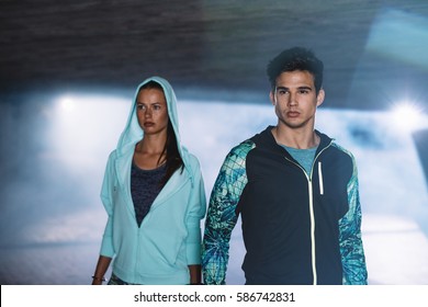 Fitness couple in city at night. Young man and woman runner in sportswear standing together in city. - Powered by Shutterstock