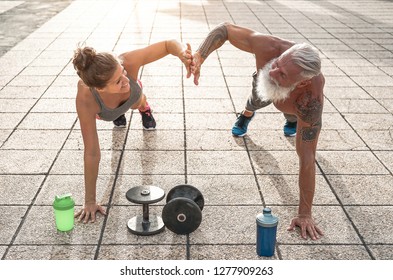 Fitness couple doing push ups exercise outdoor - Happy athletes making workout session outside - Concept of people training, fit, empowering and bodybuilding lifestyle - Powered by Shutterstock