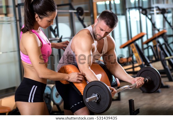 Fitness\
couple exercising in gym with barbell\
weights.