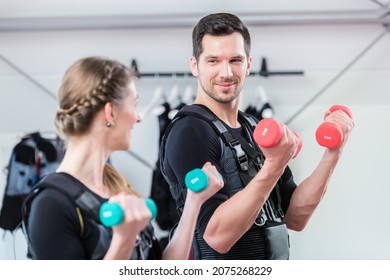 Fitness Couple Exercising With Weights In Ems Gym