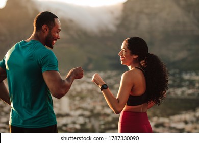 Fitness couple giving fist bump after the workout. Athletic man and woman celebrate after a run. - Powered by Shutterstock