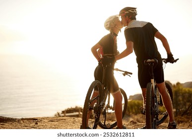 Fitness, cycling and couple on mountain with kiss, sunset sky and bonding in nature on bike. Love, man and woman embrace with bicycle, outdoor exercise and romantic travel adventure on mockup space - Powered by Shutterstock