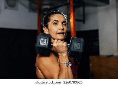 Fitness determined mature woman working out at the gym. Concetrate middle aged lady doing daily exercises. - Powered by Shutterstock