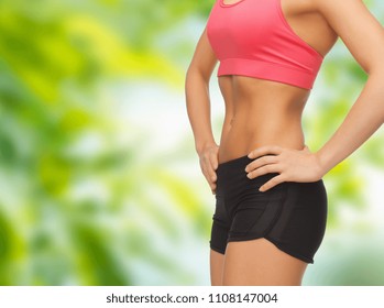 Fitness-, Diät- und Schlankheitskonzept - Nahaufnahme von weiblichem Torso und Bauch auf grünem Naturhintergrund